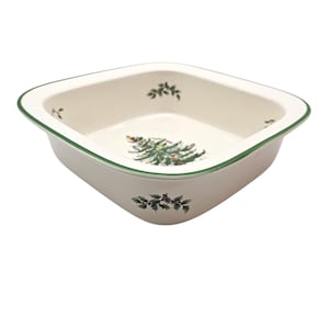 May include: A square, off-white ceramic baking dish with a green trim. The dish features a Christmas tree and holly leaf design. The interior and exterior corners are rounded. The dish is empty and ready for use.