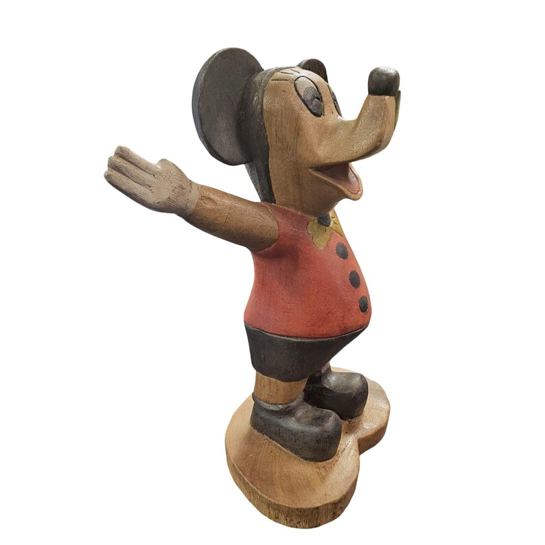 K&ouml;nnte beinhalten: Eine Holzfigur von Mickey Mouse mit ausgestreckten Armen. Die Figur ist in Braun-, Rot- und Schwarzt&ouml;nen bemalt, mit einer gelben Fliege. Der Sockel ist hellbraun und die Figur hat ein klassisches, vintage Aussehen.