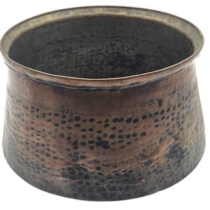 May include: A hammered copper bowl with a wide rim and a slightly tapered body. The bowl has a dark, aged patina with a pattern of small, dark spots across its surface. The interior is a darker, muted color.