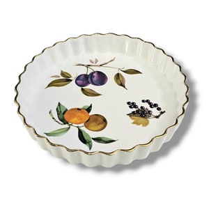 May include: White ceramic baking dish with a fluted rim and a gold trim. The dish features a floral design with plums, oranges, and blackberries.