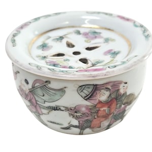 Könnte beinhalten: Ein weißer Porzellan-Räucherofen mit floralem Design und einem kleinen Loch in der Mitte. Der Räucherofen ist mit einer Szene von Menschen auf einem Pferd verziert.