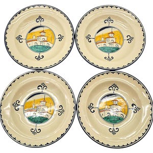 May include: A set of four ceramic plates. Each plate has a cream-coloured base, a black rim, and a central design of a building with a yellow sky and green landscape. Decorative black flourishes surround the central image.