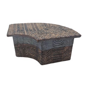 May include: A handcrafted, decorative box with a curved top and sides. The box is made of dark brown and gray textured material. The top features a woven pattern, while the sides have a geometric design.