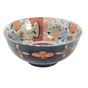 May include: A blue and white porcelain bowl with a floral design. The bowl has a dark blue rim and base with gold accents.
