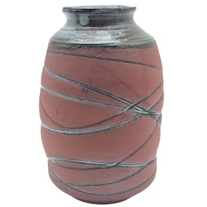 May include: A handmade ceramic vase with a reddish-brown body and a dark rim. The vase features a crisscross pattern of dark gray lines. The rim has a light blue and gray color. The vase has a rounded shape.