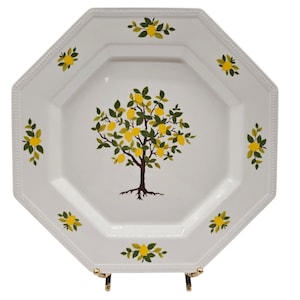 Puede incluir: Plato de cerámica octogonal blanco con un diseño de árbol de limón pintado. El árbol tiene hojas verdes y limones amarillos. El plato tiene un fondo blanco con un borde decorativo.