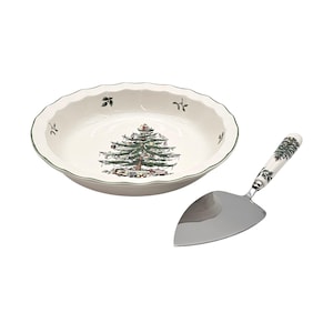 May include: A white ceramic pie dish with a green rim and a Christmas tree design. A matching pie server with a silver blade and a decorative handle featuring a Christmas tree design is included.