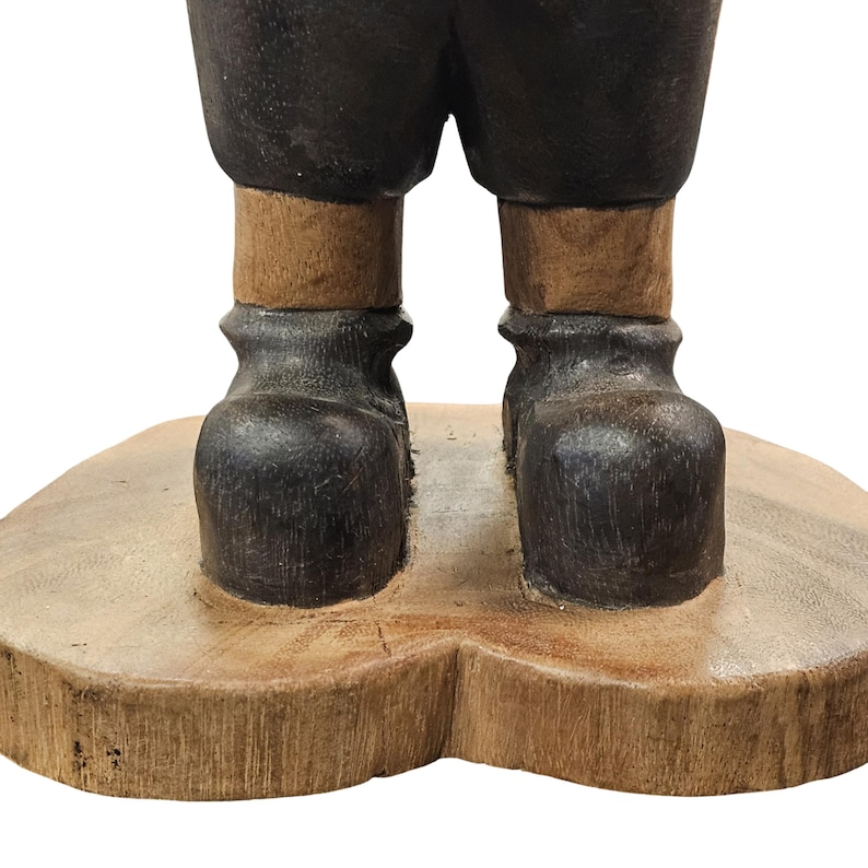 K&ouml;nnte beinhalten: Holzgeschnitzte Figur mit dunklen Stiefeln und Hosen, helleren Beinen und einem Holzsockel. Die Figur hat ein rustikales, handwerkliches Aussehen. Die Stiefel haben eine strukturierte Oberfl&auml;che.