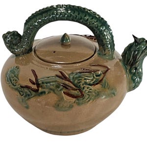 May include: A ceramic teapot with a dragon handle and spout. The teapot is decorated with a green and brown dragon design.