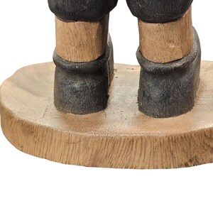 K&ouml;nnte beinhalten: Holzfigur mit Beinen und F&uuml;&szlig;en einer Person, bemalt in Braun- und Schwarzt&ouml;nen. Die Figur steht auf einem runden, hellfarbigen Holzsockel. Die Beine sind hellbraun und die Stiefel sind schwarz.