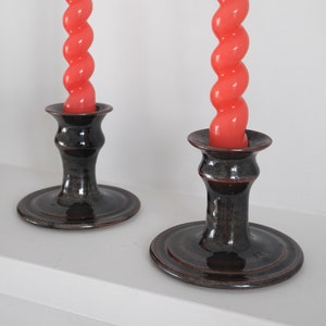 May include: Two black ceramic candle holders with a spiral orange candle in each.