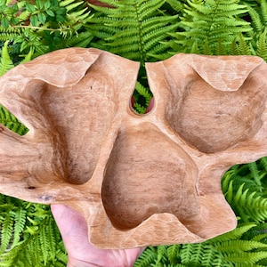 May include: A natural wood serving tray with three separate compartments. The tray is carved in a unique, organic shape and has a light brown colour.