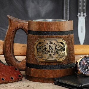 May include: A wooden beer stein with a black band and a gold metal plaque that reads "The Dice Giveth & The Dice Taketh Away Robert".