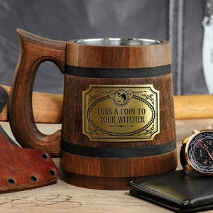 May include: A wooden beer stein with a metal band and a brass plaque that reads "Toss a coin to your Witcher".