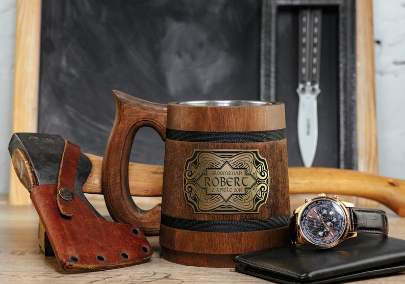 May include: A wooden beer stein with a black band and a gold metal plaque with the text "Groomsbman Robert 12 April 2023".