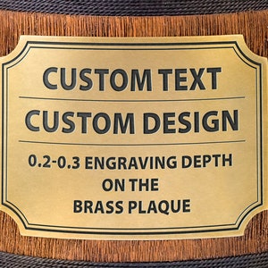 Pode incluir: Uma placa de lat&atilde;o dourada com uma borda preta e cantos arredondados. A placa tem o texto "CUSTOM TEXT" e "CUSTOM DESIGN" em letras pretas. Abaixo do texto est&aacute; a frase "0.2-0.3 ENGRAVING DEPTH ON THE BRASS PLAQUE".