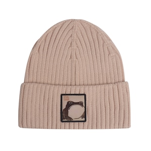 May include: A beige knitted beanie with a brown frog graphic and the text "The Frog King" on a white background.