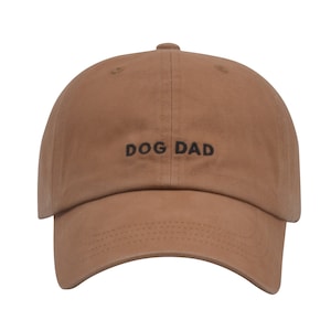 May include: A brown baseball cap with the text "DOG DAD" embroidered in black on the front.