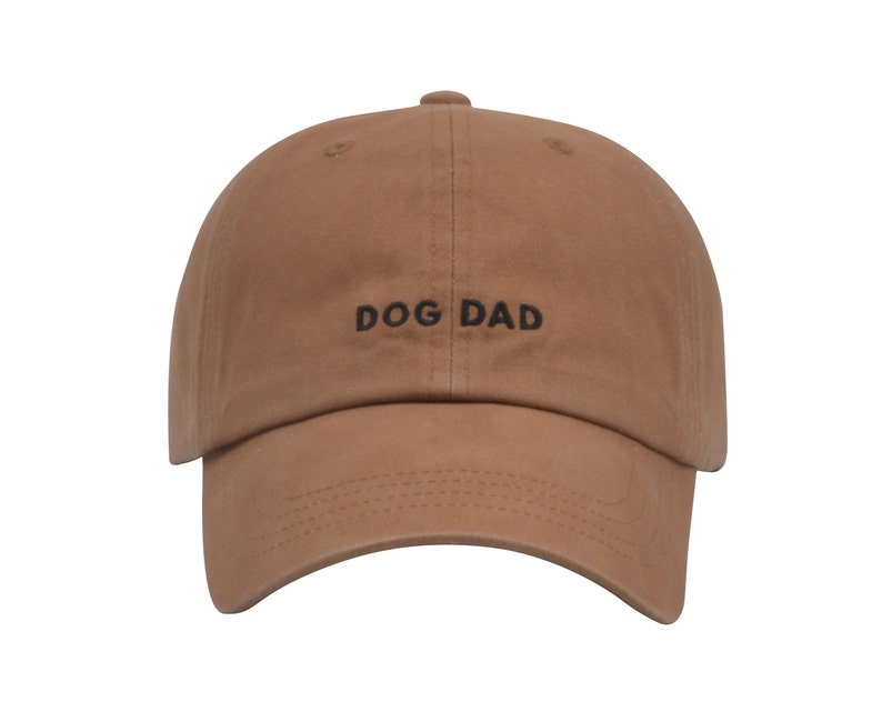 May include: A brown baseball cap with the text "DOG DAD" embroidered in black on the front.