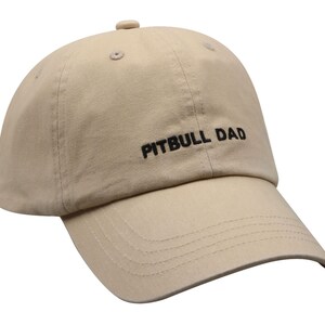 May include: A beige baseball cap with black embroidery that reads "PITBULL DAD".