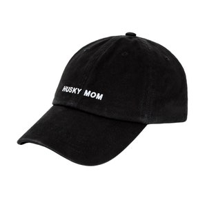 K&ouml;nnte beinhalten: Eine schwarze Baseballkappe mit einer wei&szlig;en Stickerei, die "HUSKY MOM" lautet.