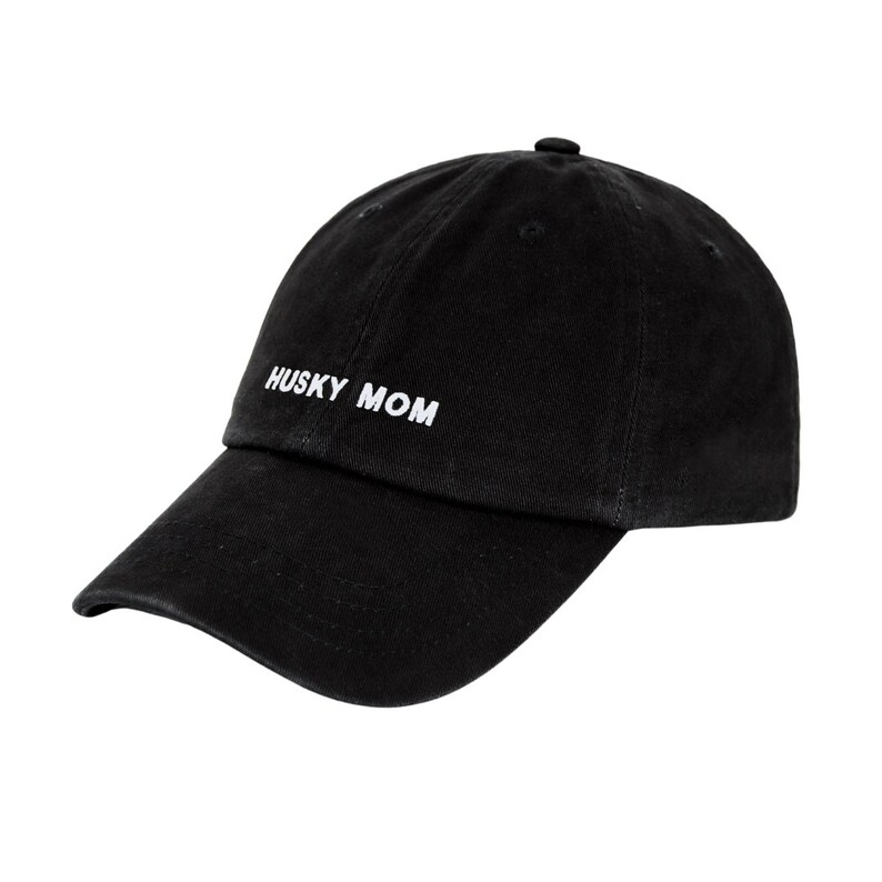 K&ouml;nnte beinhalten: Eine schwarze Baseballkappe mit einer wei&szlig;en Stickerei, die "HUSKY MOM" lautet.