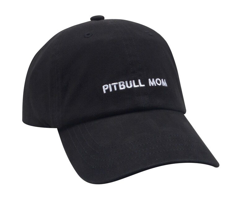 May include: Black baseball cap with white embroidered text that reads "PITBULL MOM".