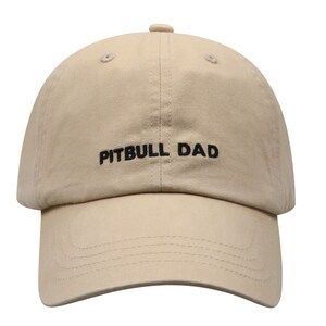 May include: A beige baseball cap with black embroidery that reads "PITBULL DAD".