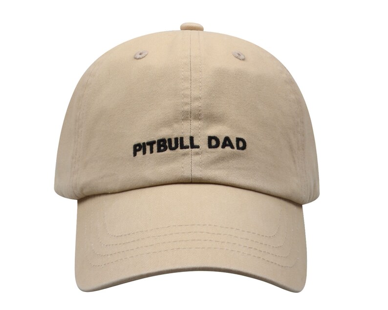 May include: A beige baseball cap with black embroidery that reads "PITBULL DAD".
