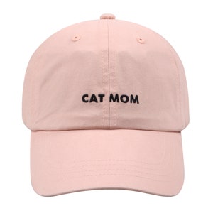 Pu&ograve; includere: Un berretto da baseball rosa con ricamo nero che recita "CAT MOM".