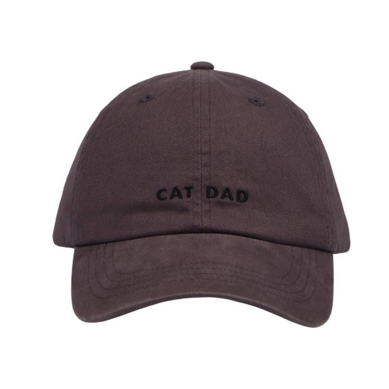 May include: A dark gray baseball cap with the text "CAT DAD" embroidered in black on the front.