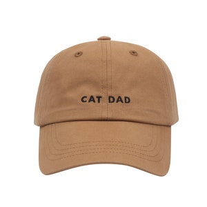 May include: A brown baseball cap with the text "CAT DAD" embroidered in black on the front.