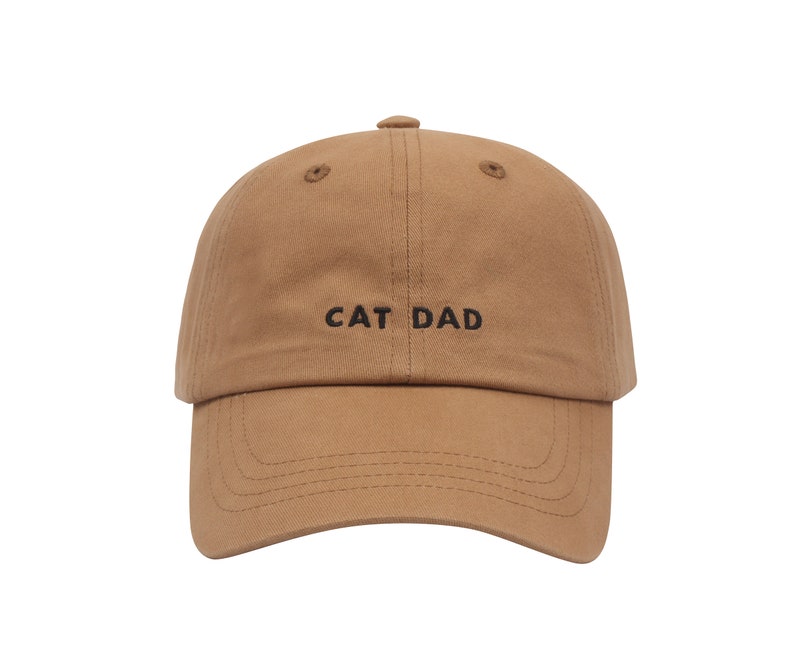 May include: A brown baseball cap with the text "CAT DAD" embroidered in black on the front.