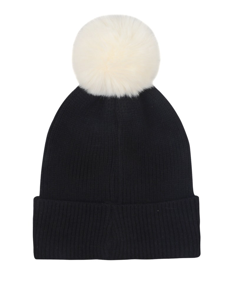 May include: Black knit beanie with a white faux fur pom pom on top.