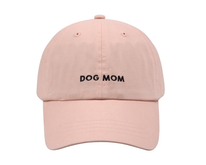 May include: A pink baseball cap with the text "DOG MOM" embroidered in black on the front.