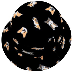 May include: Black bucket hat with a repeating pattern of cartoon corgis in various poses. The corgis are brown, white, and orange.