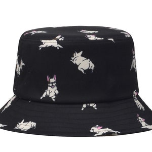May include: Black bucket hat with a white French bulldog pattern. The hat has a wide brim and a flat crown.