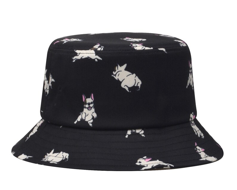 May include: Black bucket hat with a white French bulldog pattern. The hat has a wide brim and a flat crown.