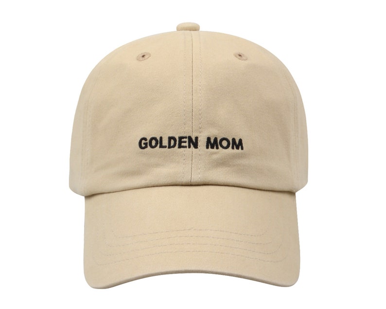 May include: A beige baseball cap with black embroidery that reads "GOLDEN MOM".