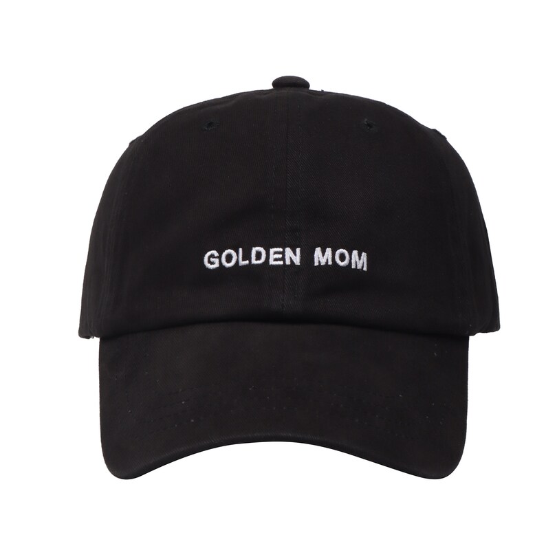 May include: Black baseball cap with white embroidered text that reads "GOLDEN MOM".
