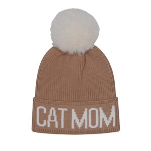 Puede incluir: Un gorro de punto marr&oacute;n con un pomp&oacute;n blanco y el texto "CAT MOM" en blanco.