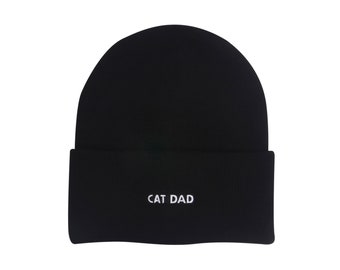 May include: Black knit beanie with a white embroidered "CAT DAD" text.
