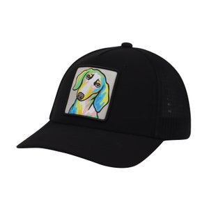 Op de afbeelding: Zwarte truckercap met een kleurrijk cartoon-hondje op de voorkant.