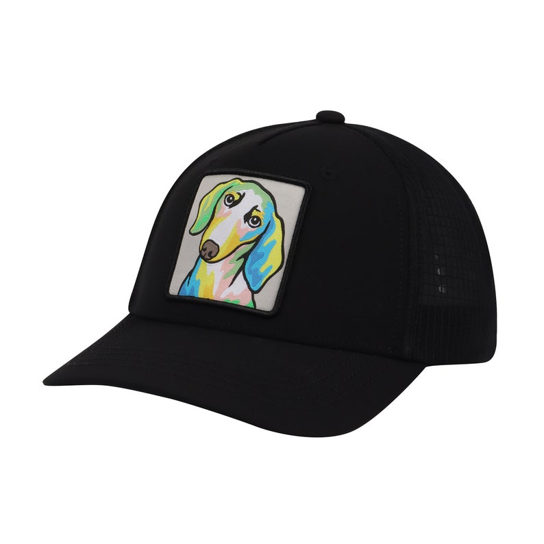 Op de afbeelding: Zwarte truckercap met een kleurrijk cartoon-hondje op de voorkant.