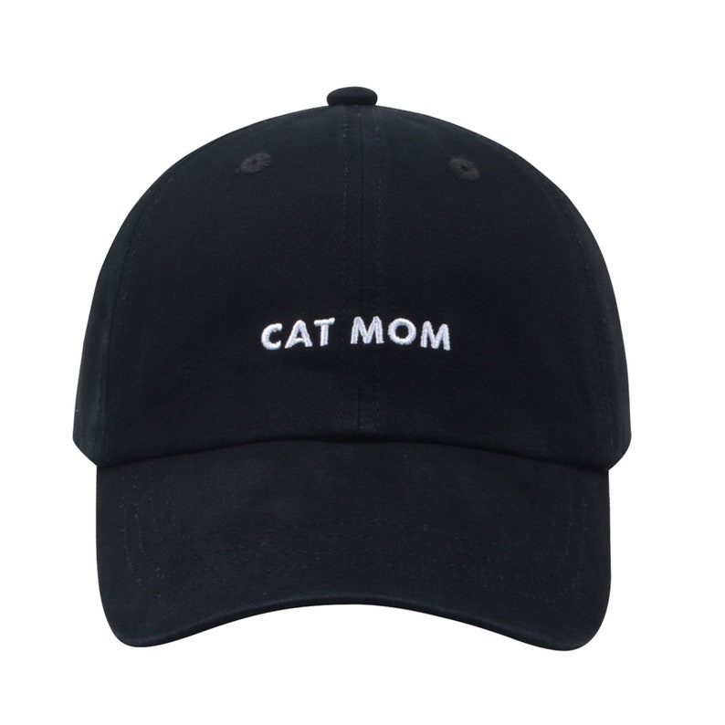 Pu&ograve; includere: Un cappello da baseball nero con ricamo bianco che dice "CAT MOM".
