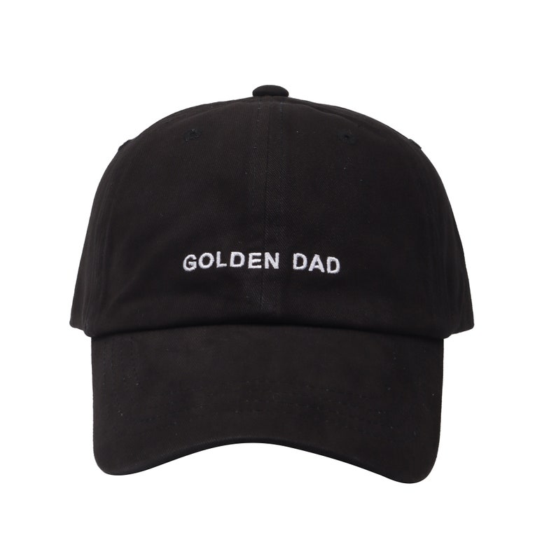 May include: Black baseball cap with white embroidered text that reads "GOLDEN DAD".