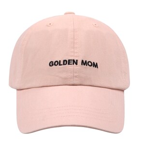May include: A pink baseball cap with the text "GOLDEN MOM" embroidered in black.