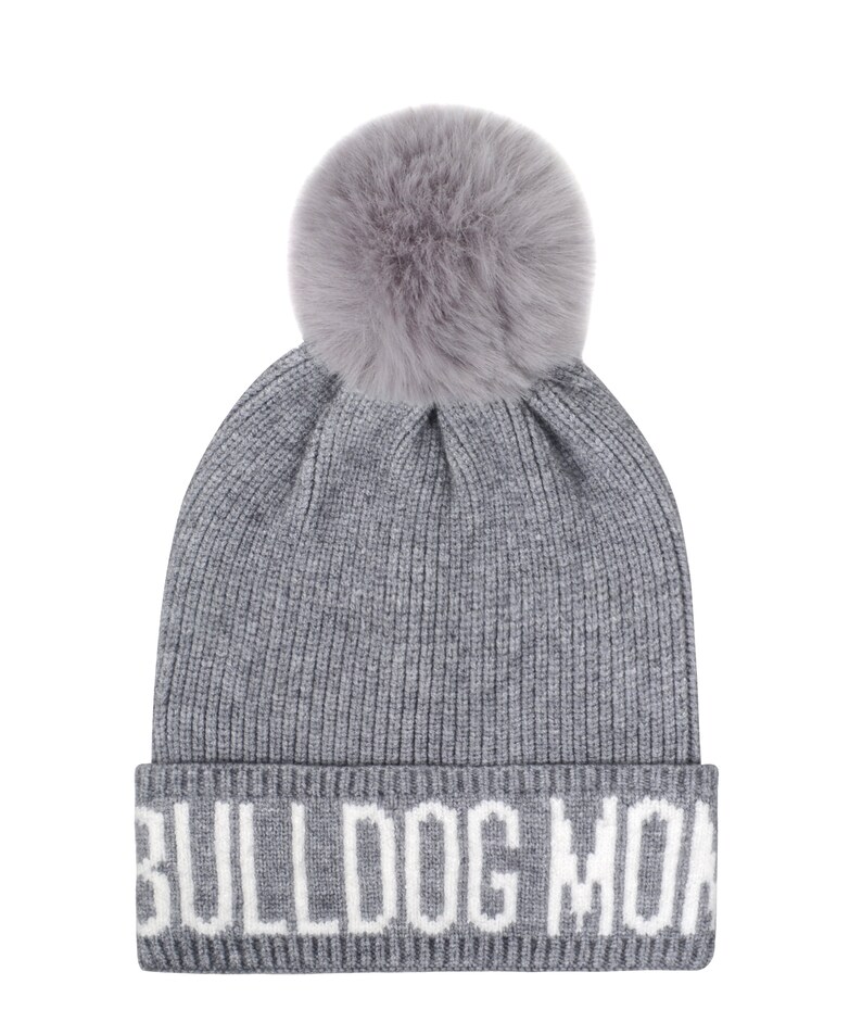 Pode incluir: Um gorro cinza de malha com um grande e fofo pompom cinza no topo. A aba dobrada apresenta o texto branco "BULLDOG MON". Um chap&eacute;u de inverno moderno para os meses mais frios.