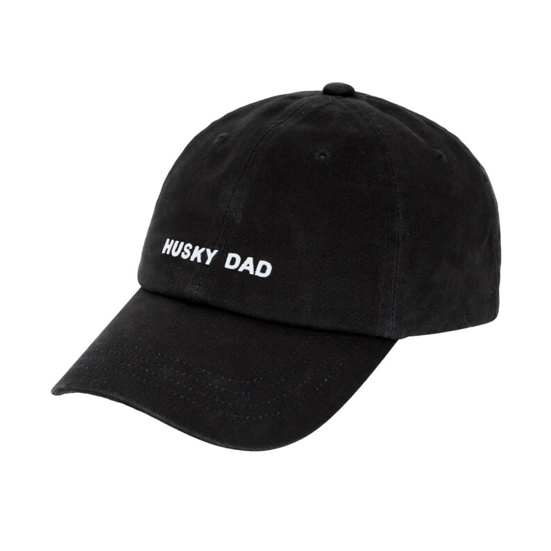 K&ouml;nnte beinhalten: Eine schwarze Baseballkappe mit einer wei&szlig;en Stickerei, die "HUSKY DAD" lautet.