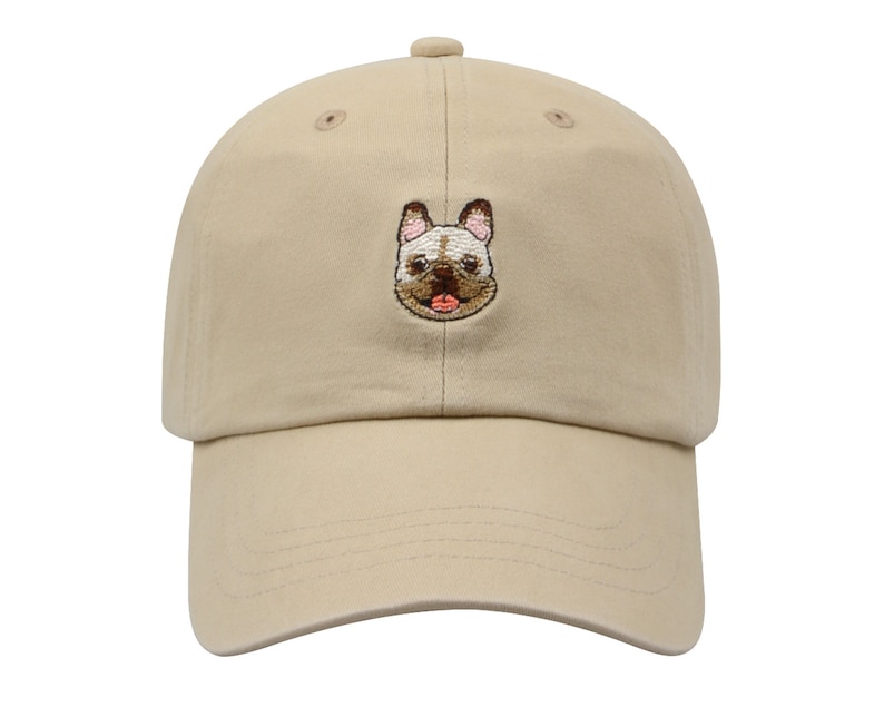 May include: A beige baseball cap with an embroidered image of a French bulldog on the front.